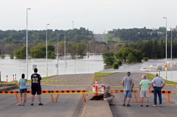 Tim Smith/Brandon Sun
Brandonites watch the flood waters of the Assiniboine River pour over First Street from the First Street Bridge in 2014. According to the latest flood forecast, this spring won't be nearly as wet. (File)