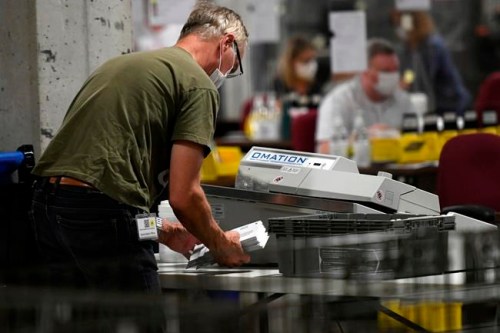 A worker uses a envelope cutting machine as they open special ballots from national, international, Canadian Forces and incarcerated electors at Elections Canada's distribution centre in Ottawa on election night of the 44th Canadian general election, on Monday, Sept. 20, 2021. THE CANADIAN PRESS/Justin Tang