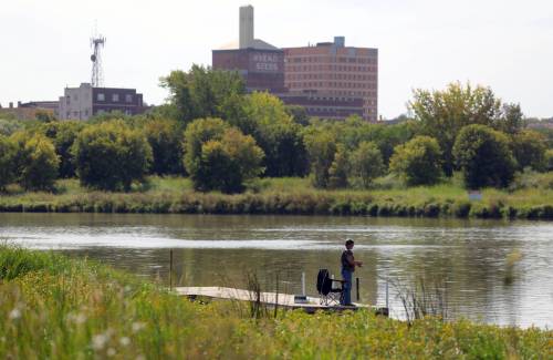 An angler fishes at Dinsdale Park backdropped by the city's downtown skyline. Deveryn Ross writes that Brandon faces a deficit of community groups that are traditionally responsible for organizing local projects. 