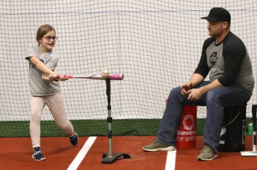 Fieldhouse owner and operator Tyler Ursel keeps the baseballs coming as his daughter Ruby gets some cuts in off the tee in the batting cage. (Perry Bergson/The Brandon Sun)