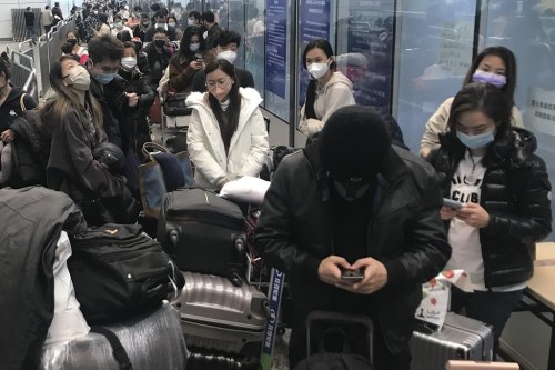 Inbound travelers waiting for hours to board buses to leave for quarantine hotels and facilities from Guangzhou Baiyun Airport in southern China's Guangdong province on Dec. 25 2022. The national public health agency says it's 