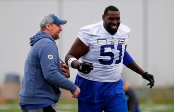 Winnipeg Blue Bombers head coach Mike O'Shea jokes around with Jermarcus Hardrick (51) during practice at training camp in Winnipeg Thursday, May 19, 2022. The Blue Bombers signed the veteran American offensive tackle Hardrick to a one-year contract extension Wednesday.THE CANADIAN PRESS/John Woods