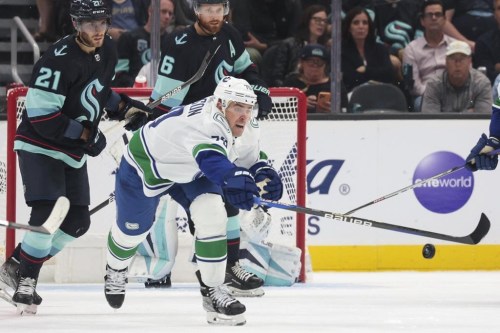 Vancouver Canucks forward Tanner Pearson reaches for the puck as Seattle Kraken forward Alex Wennberg (21) and defenceman Adam Larsson (6) watch during the second period of a preseason NHL hockey game Saturday, Oct. 1, 2022, in Seattle. Vancouver Canucks forward Tanner Pearson will miss the rest of the season due to an ongoing hand injury. THE CANADIAN PRESS-AP/Jason Redmond