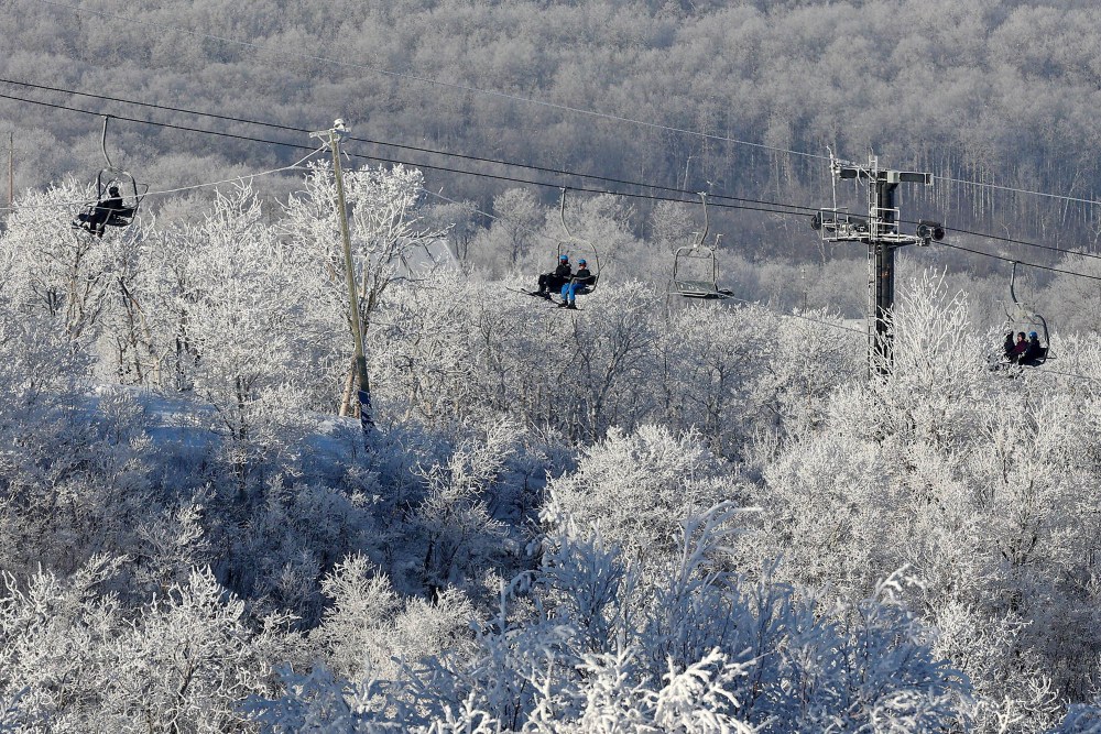 Skiers and snowboarders ride a chairlift, framed by hoar frost, during a crisp day of winter activities at Asessippi Ski Resort on a sunny day in early January. (Tim Smith/The Brandon Sun)
