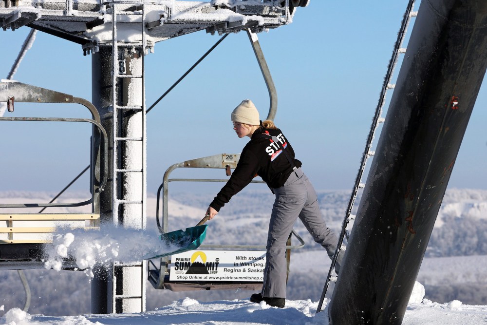 A worker at Asessippi Ski Resort adds snow to where skiers dismount from a chair lift on a sunny day in early January. (Tim Smith/The Brandon Sun)